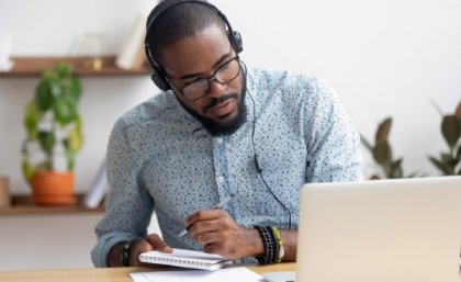 Man studying at desk with headphones on.